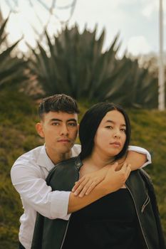 A young couple poses warmly outdoors, surrounded by lush greenery. - Fotografer Sidoarjo