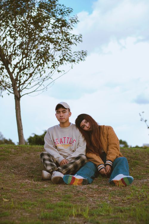 Free Two young adults sitting on a grassy hill in autumn, embodying peacefulness and connection. Stock Photo