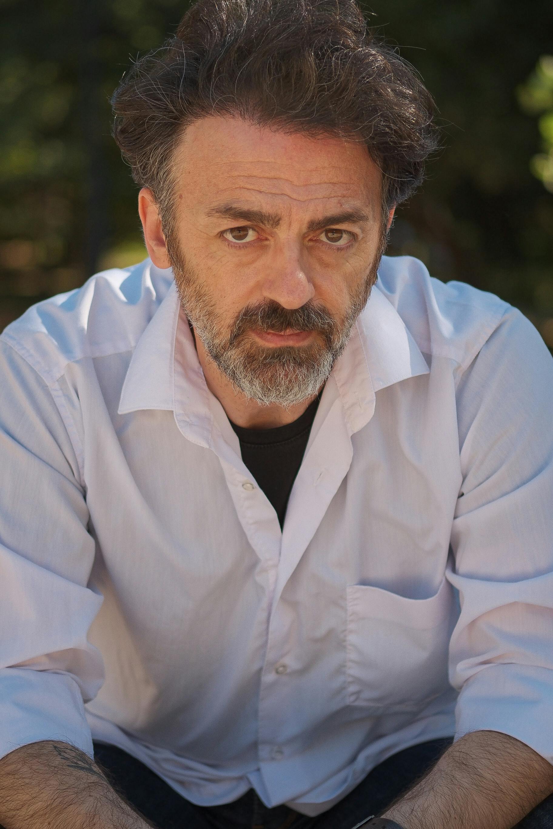 Close-up portrait of a thoughtful man wearing a white shirt outdoors.