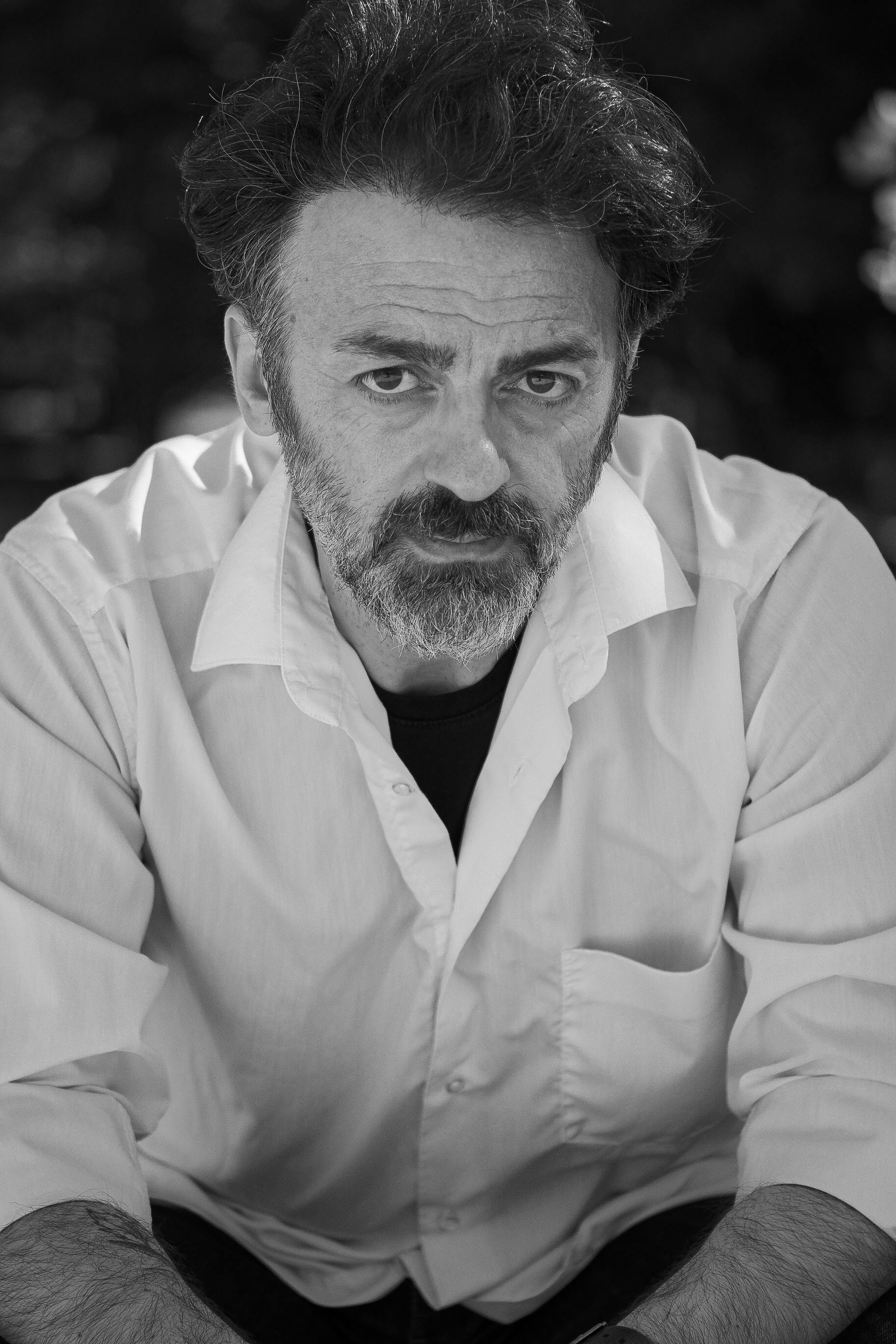 Introspective black and white portrait of a man with a serious expression, wearing a white shirt.