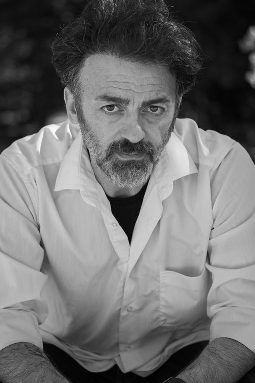 Free Introspective black and white portrait of a man with a serious expression, wearing a white shirt. Stock Photo