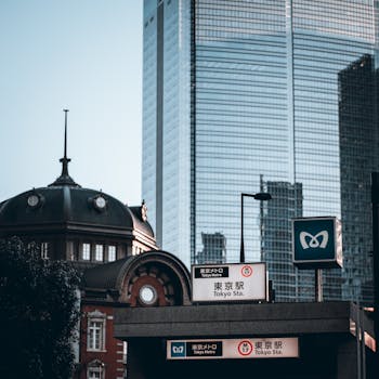 View of Tokyo Station with a modern skyscraper in the background, embodying urban contrast.
