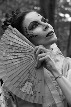 Black and white portrait of a woman in traditional attire holding a decorative fan.