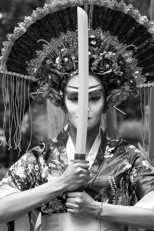 Free Black and white portrait of a woman in traditional costume and headdress holding a sword. Stock Photo