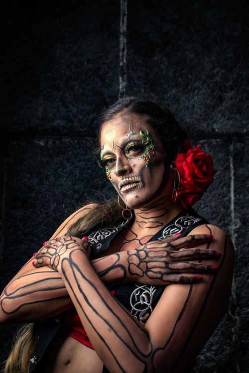 Free Stunning portrait of a woman with detailed skeleton makeup and red rose accessory. Stock Photo