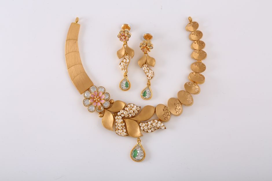 Sophisticated gold necklace set with floral patterns and gemstone embellishments, perfect for special occasions.