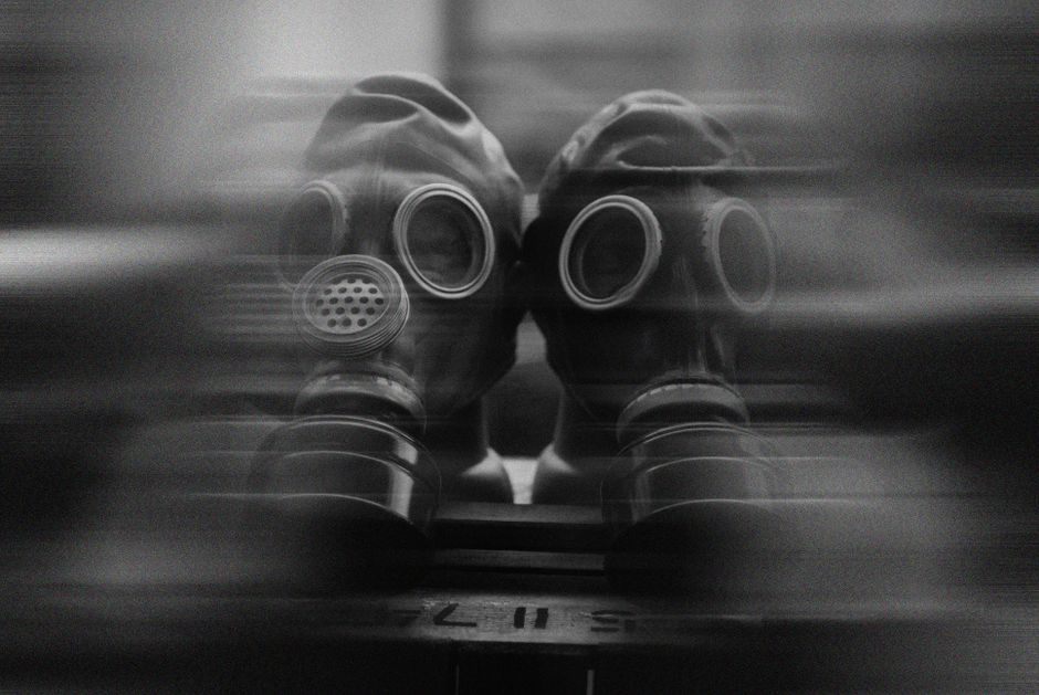 Two gas masks captured in a surreal, blurred black and white image.