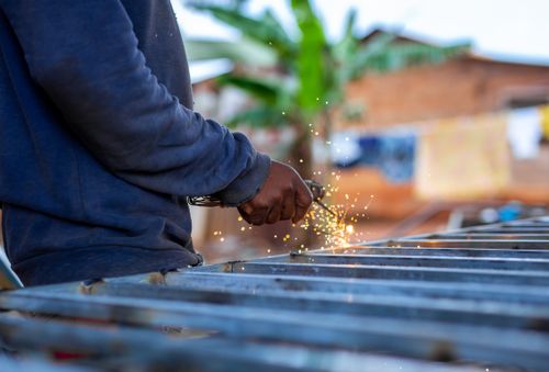Free A person welding metal outdoors, creating bright sparks against a blurred background. Stock Photo