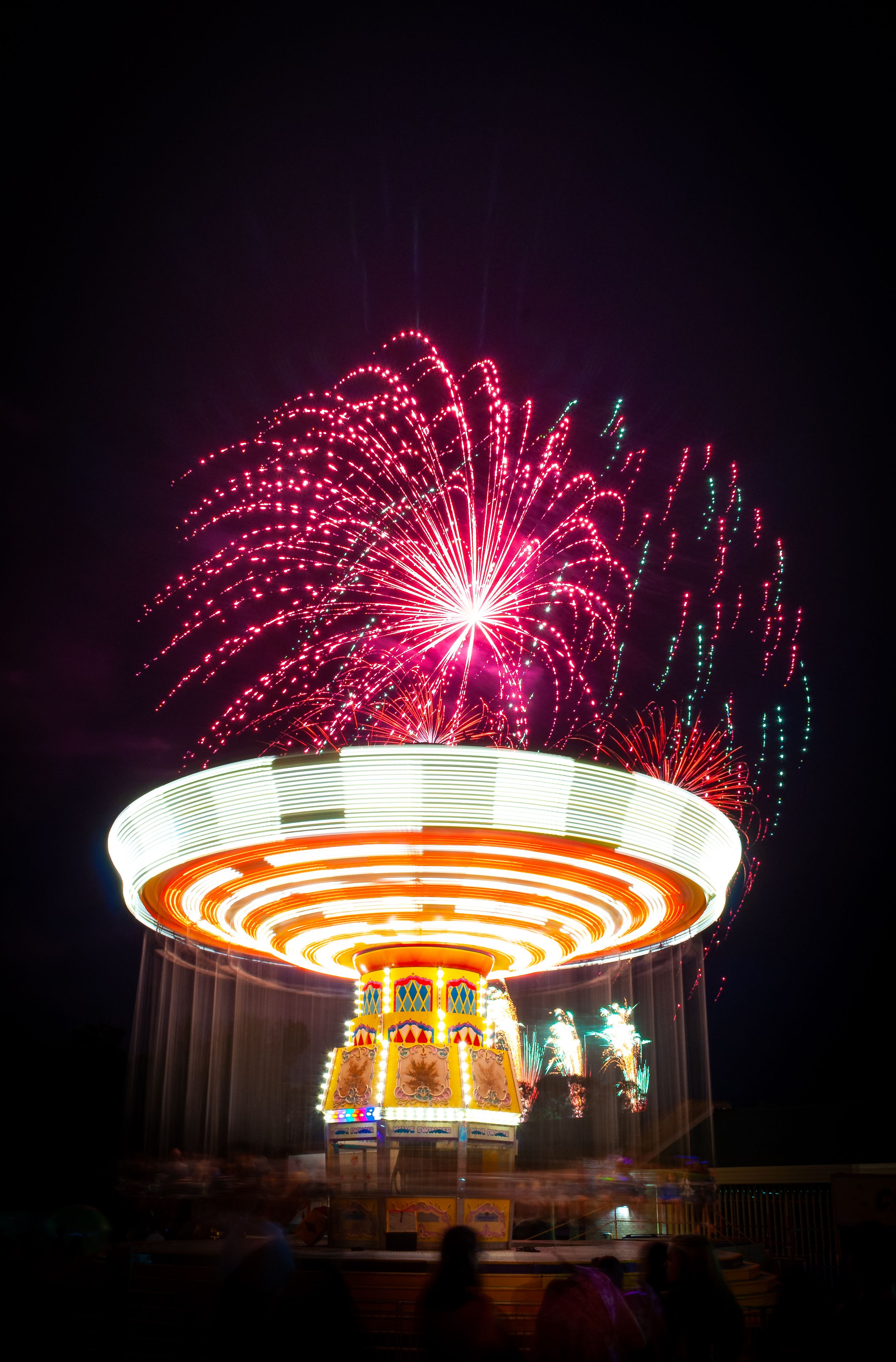 Vibrant Fireworks Over Amusement Park Ride at Night · Free Stock Photo