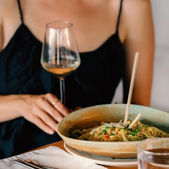 Elegant dining experience with white wine and Asian noodles, perfect for a sophisticated meal.