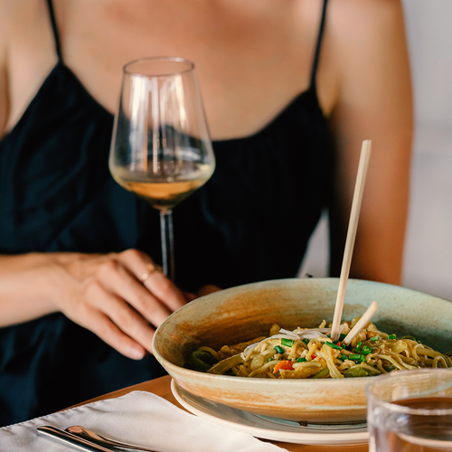 Free Elegant dining experience with white wine and Asian noodles, perfect for a sophisticated meal. Stock Photo