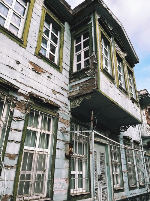 Free Charming weathered building featuring green-trimmed windows in an urban landscape. Stock Photo
