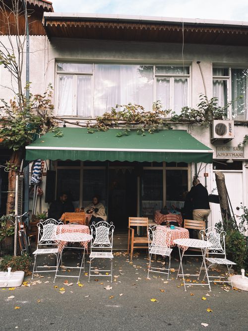 Free Charming street café with vintage seating and greenery outside a building. Stock Photo