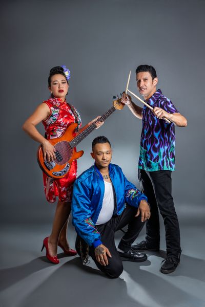 Trio posing with bass and drumsticks in studio — Taina Medeiros on Pexels