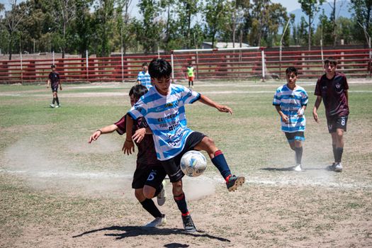 Intense moment in a youth soccer match on a sunny day with players in action.