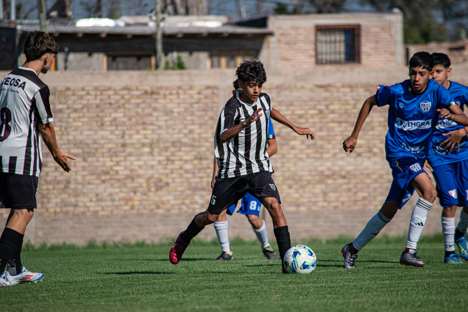 Intense youth soccer match with players competing outdoors on a sunny day.