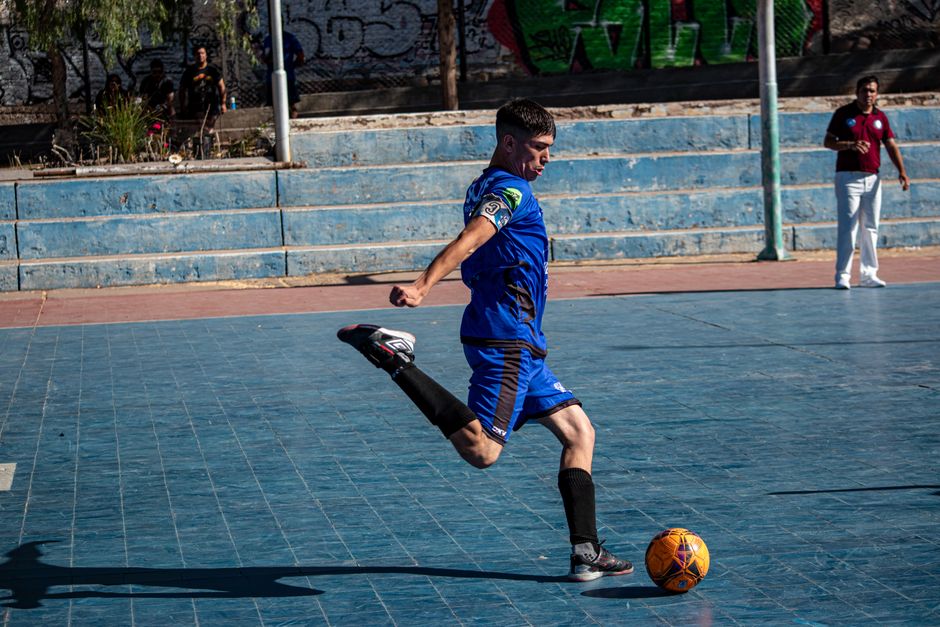 Dynamic shot of a young man skillfully playing soccer on an urban court.