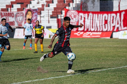 Dynamic soccer match capturing a player mid-kick on a sunny day, showcasing teamwork and agility.