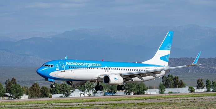 Aerolineas Argentinas jet landing against mountainous backdrop in Argentina.