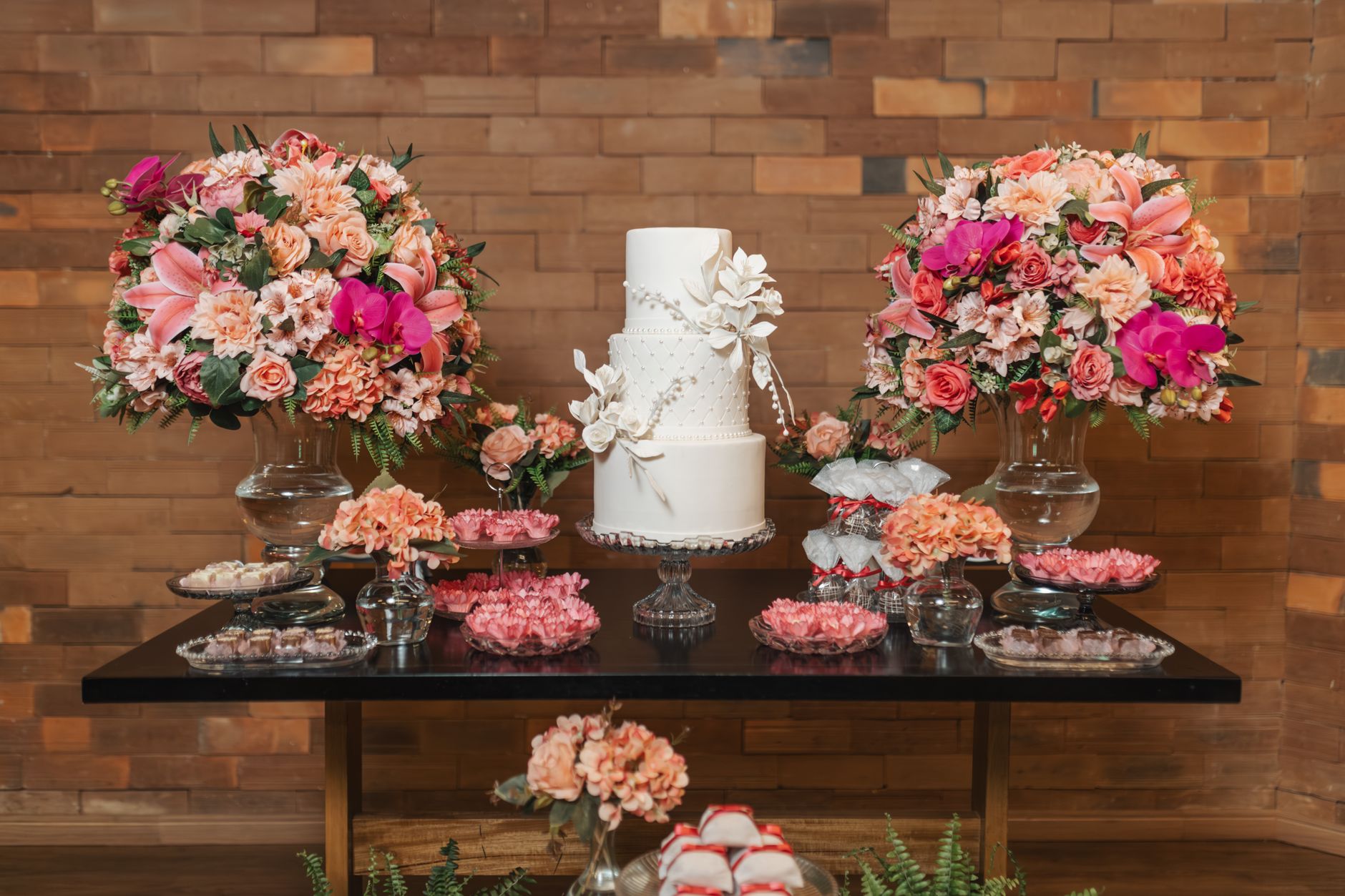 A beautiful wedding cake with floral decor on a table setting indoors.