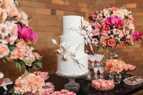 Free A beautiful white wedding cake surrounded by vibrant floral arrangements. Stock Photo