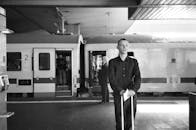 火车站里，一名男子提着箱子站在黑白照片中