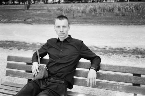 Monochrome Photo Of Man Sitting On Wooden Bench