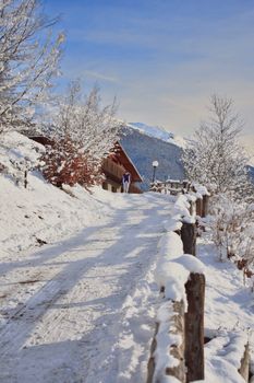 Snow-covered path leading to a cozy mountain cabin, surrounded by winter scenery.