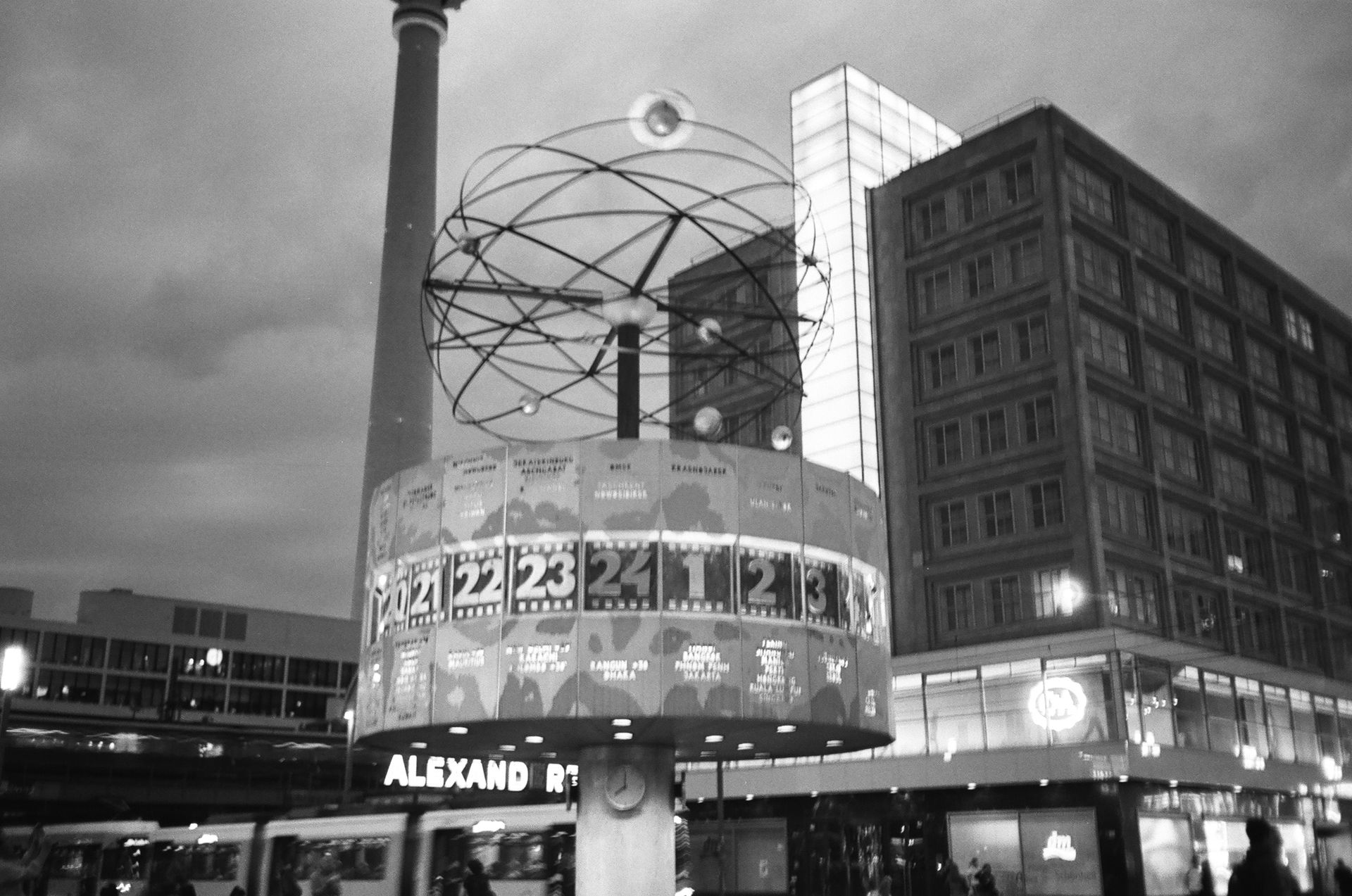 Black and white photo of the World Clock at Alexanderplatz, Berlin, illuminated at night.