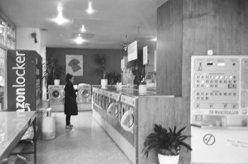 Woman in Black Coat Standing Beside Washer Dryers