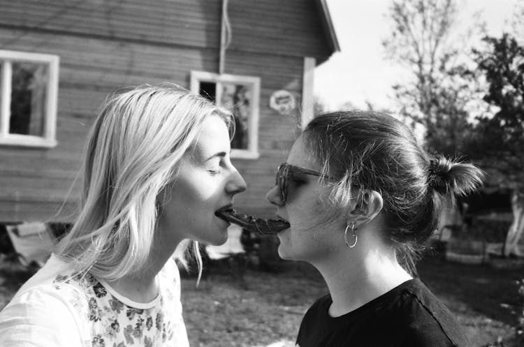 Grayscale Photography Woman Eating Hotdog Outdoors