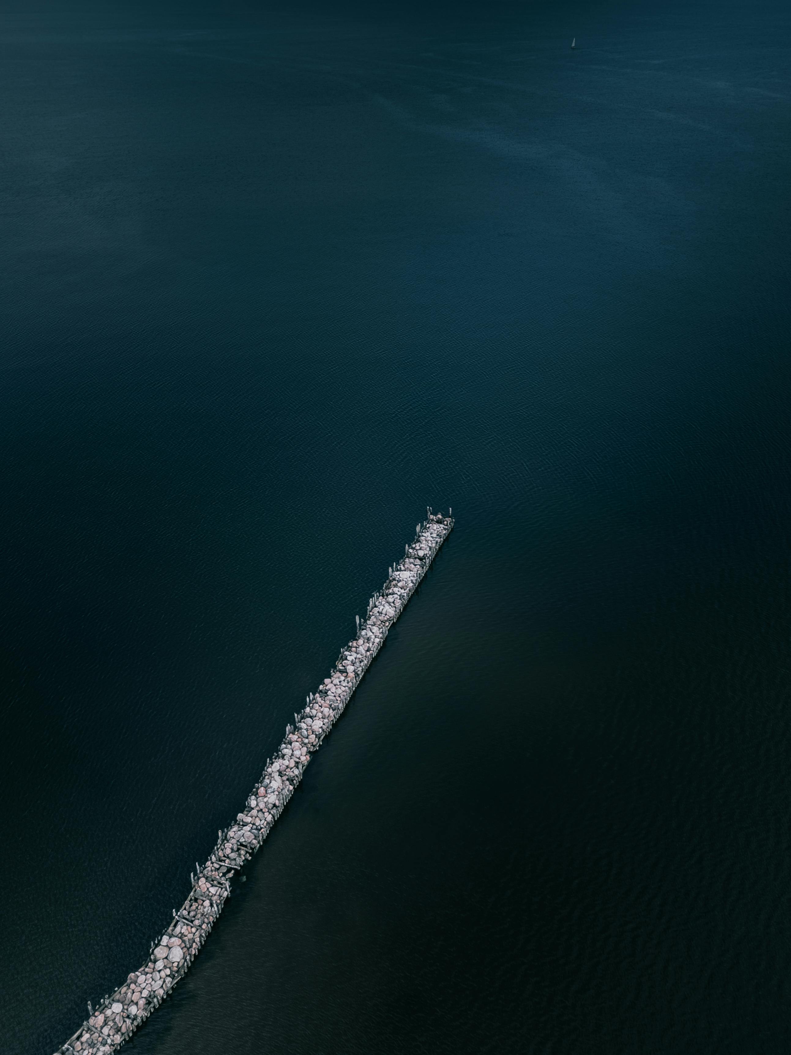 Gratis Fantastisk luftfoto av en lang molo som strekker seg ut i rolig blågrønt vann, rolig sjølandskap. Arkivbilde