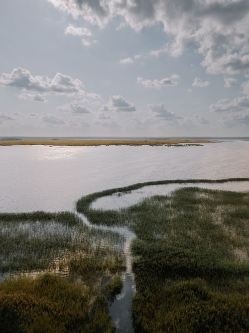 Free Serene aerial shot of a coastal marshland under a cloudy sky, ideal for nature themes. Stock Photo