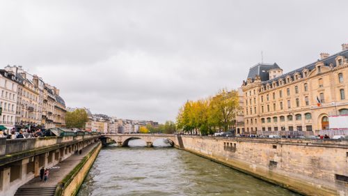 Free Scenic autumn view of a bridge and river in Paris with historic buildings lining the Seine. Stock Photo
