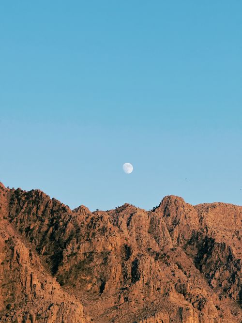 Free Stunning view of the moon rising above rugged mountains in Iraq under a clear blue sky. Stock Photo