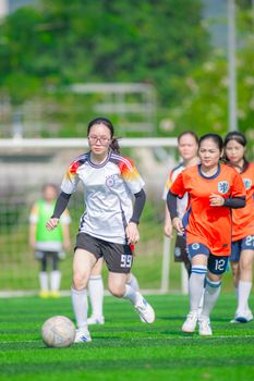 Female soccer players in action during a match on a sunny day in Hanoi, Vietnam.
