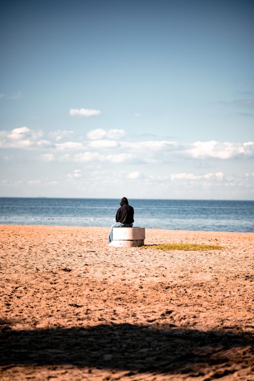 Free A single person sits contemplatively on a beach facing the serene ocean in Yalova, Türkiye. Stock Photo