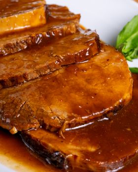 Delicious roast beef slices drenched in rich, savory gravy on a plate.