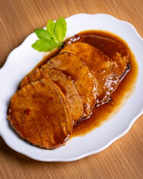 Delicious slices of roast beef topped with rich gravy, garnished with fresh greens.
