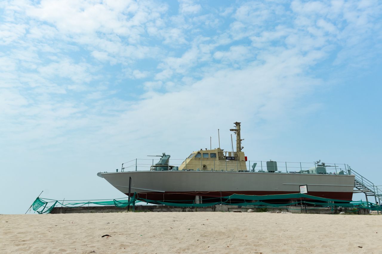 a ship docked on the sandy shores of alappuzha beach under a clear blu