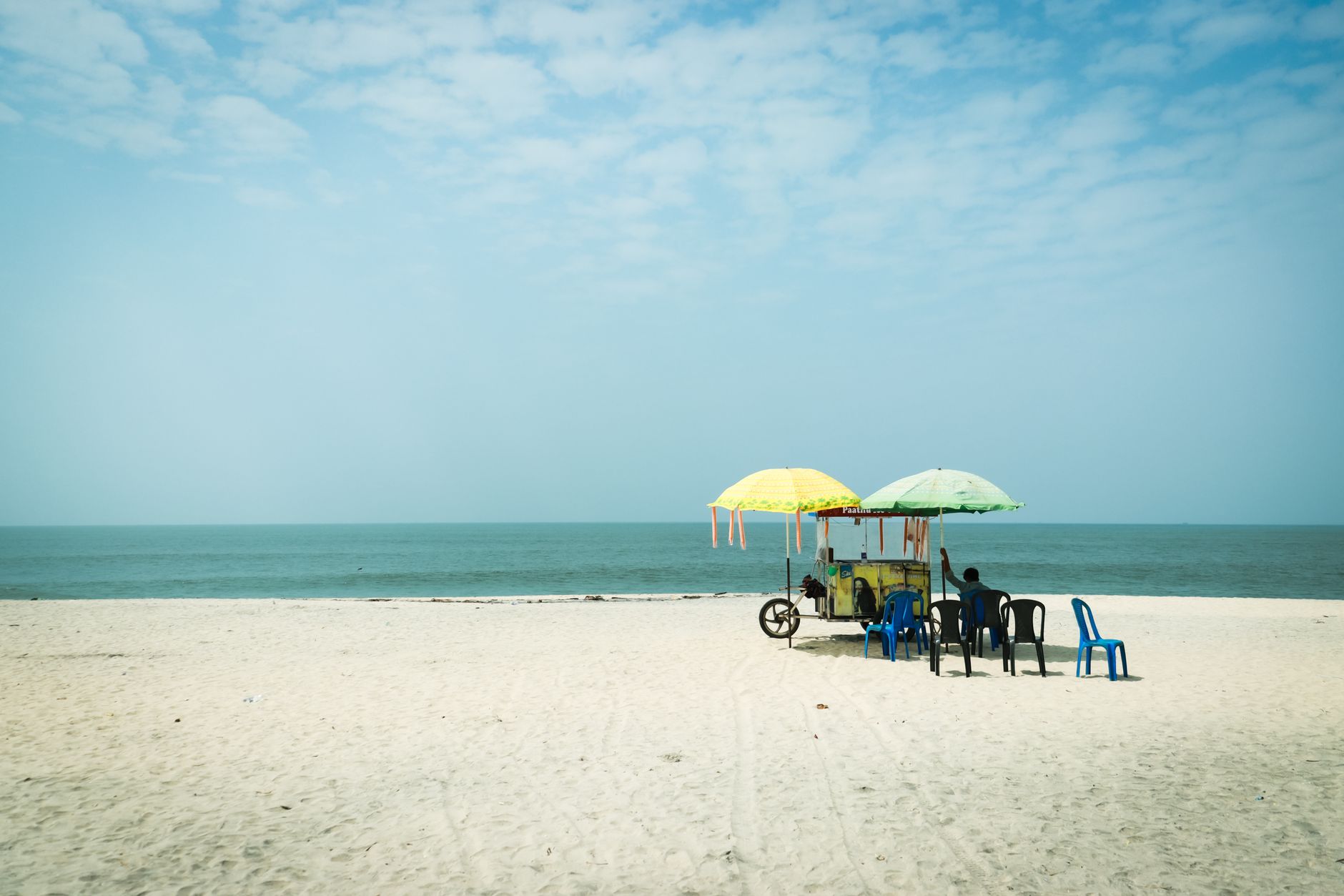 Peaceful beach with chairs and cart in Alappuzha, Kerala, capturing serenity.