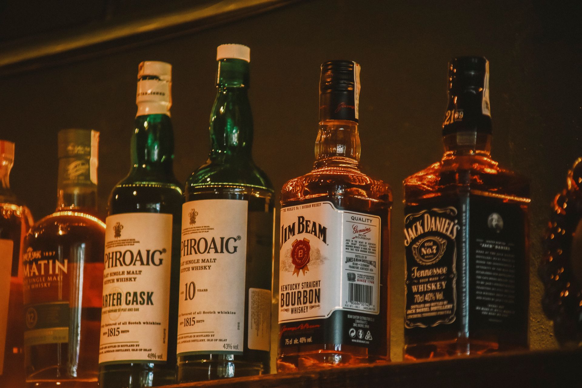Colecao de whiskies premium em prateleira com iluminacao quente de bar