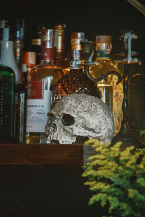 Free An artistic display with a skull, bottles, and candles, creating a mysterious bar ambiance. Stock Photo