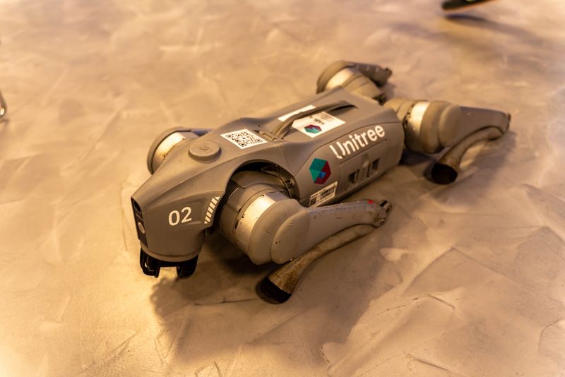 A Unitree-branded quadruped robot, number 02 visible on its body, rests on a showroom floor