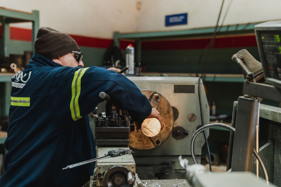 Machinist operating a lathe to turn a metal component