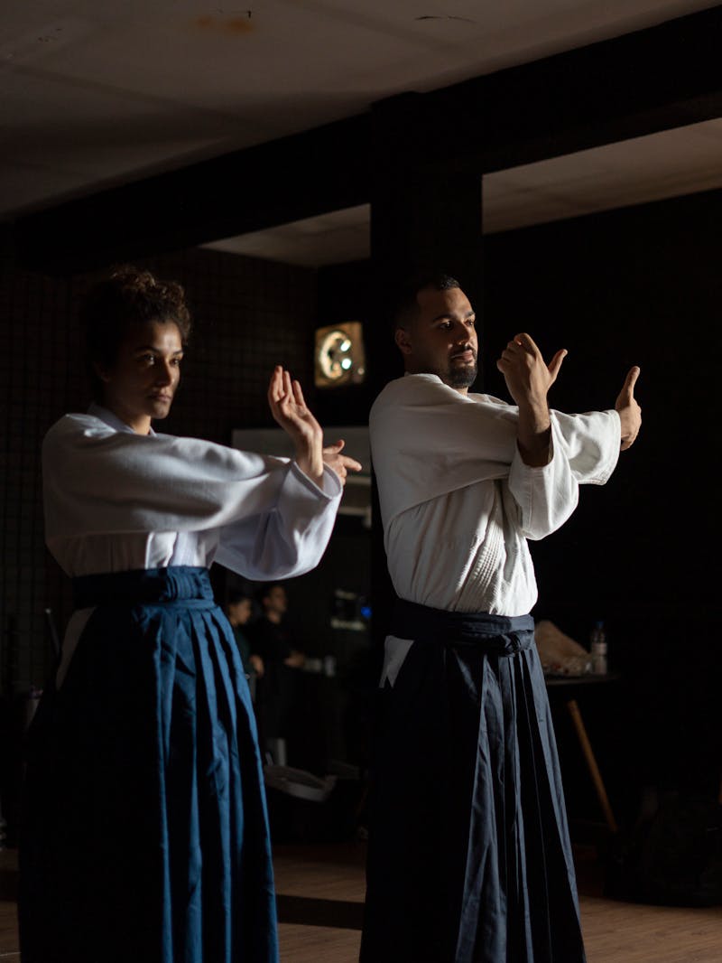 Two martial arts practitioners in traditional attire engaged in focused Wing Chun partner training