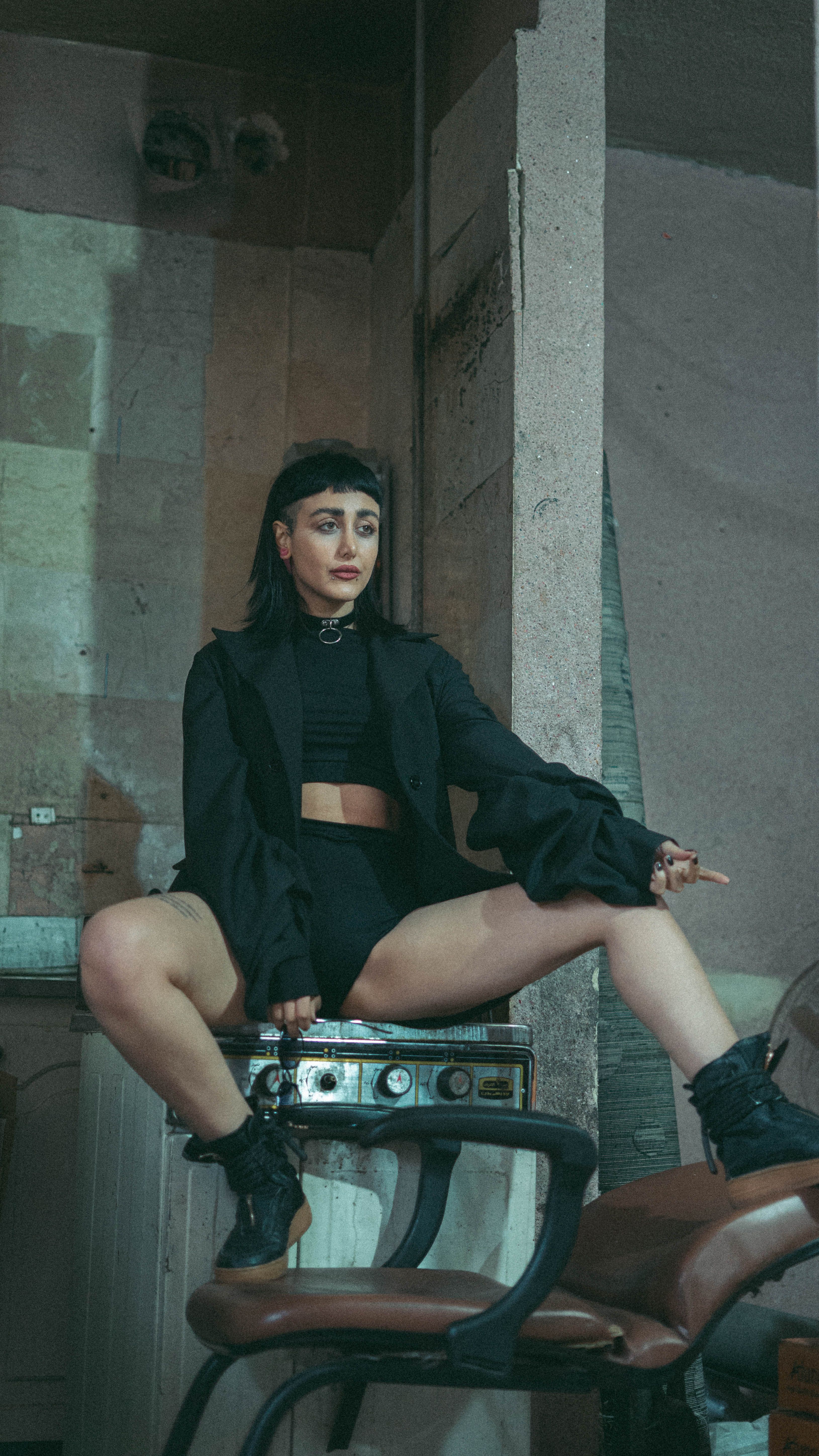 A young woman strikes a bold pose in avant-garde fashion against an industrial backdrop.