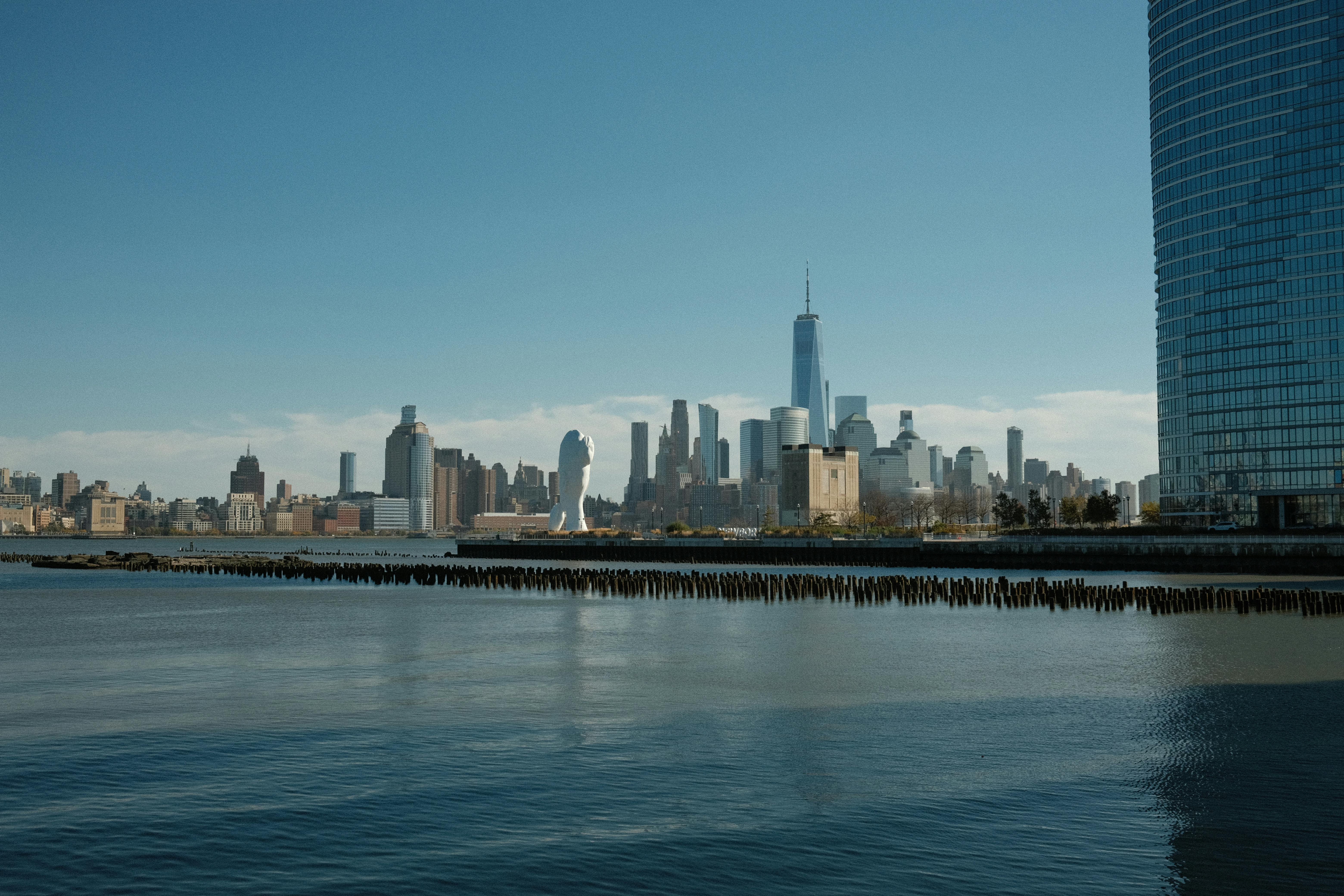 Panoramic view of New York City skyline captured from Jersey City waterfront on a clear day.