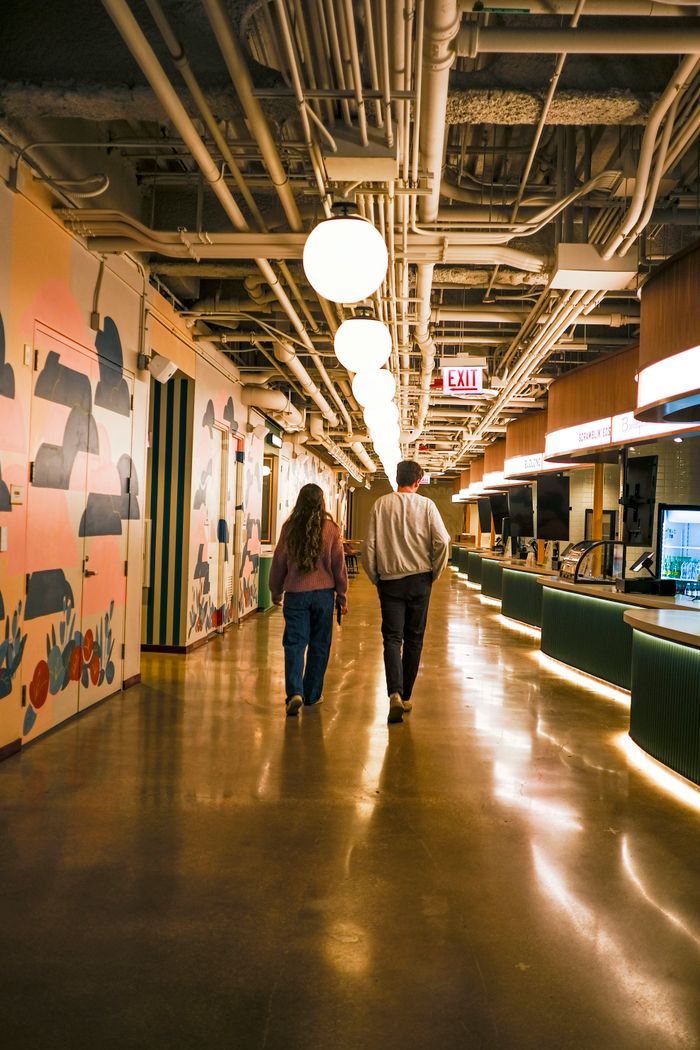 Two people walking through a designed hallway — photo by Sydney Sang on Pexels