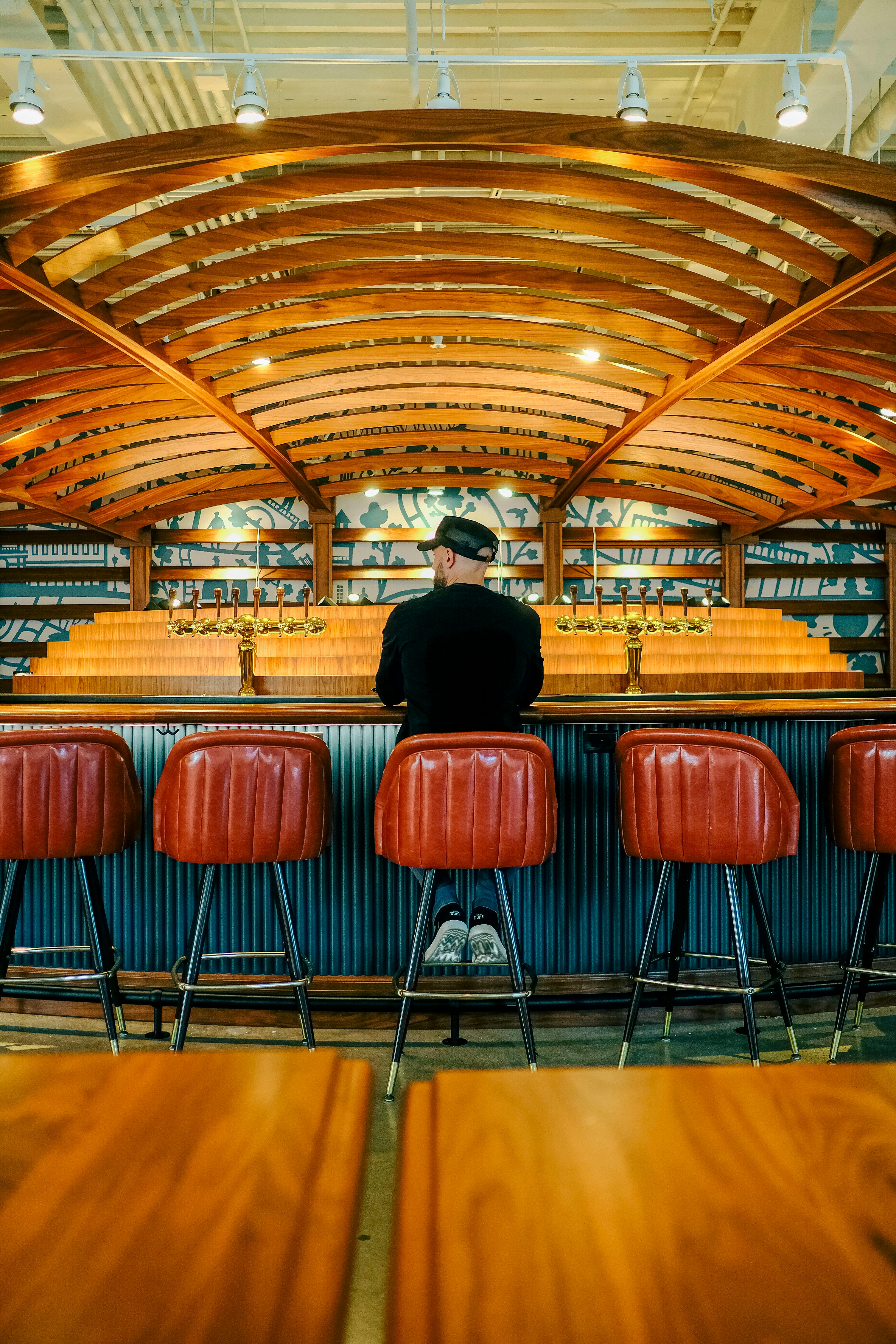 man sitting alone at a rustic bar with arch ceiling